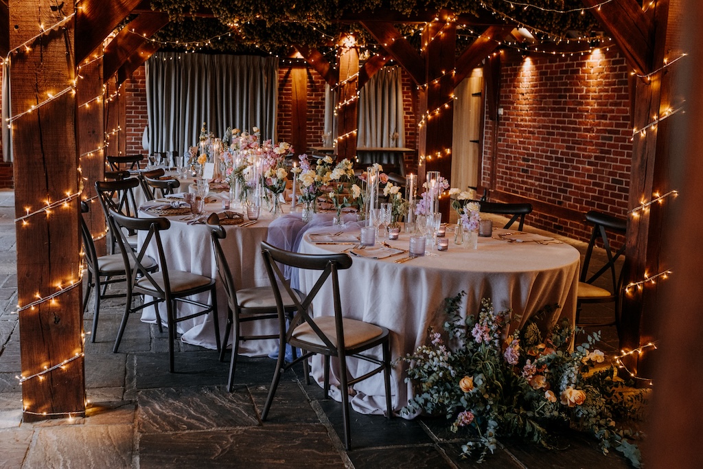 Barn venue styled for an intimate wedding breakfast with curved caterpillar tables