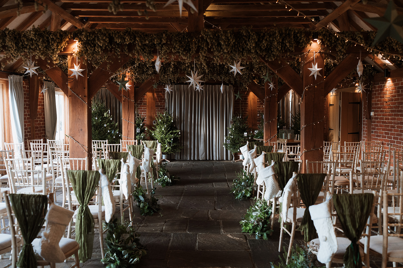 Christmas ceremony with pine trees and stockings at a barn wedding venue in Kent