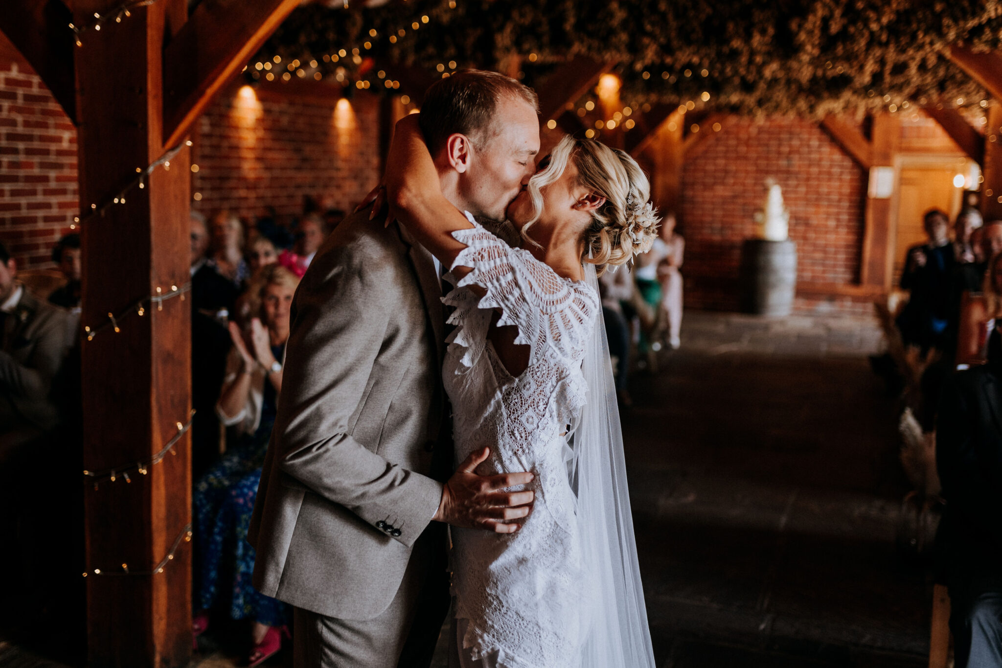 Couple sharing their first kiss during a barn wedding ceremony in Kent