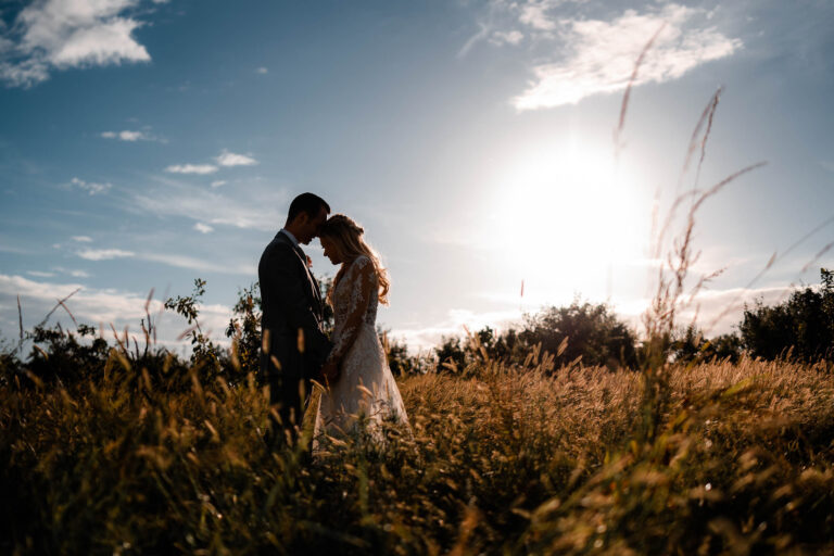 Tender moment for a wedding couple at twilight among golden grasses