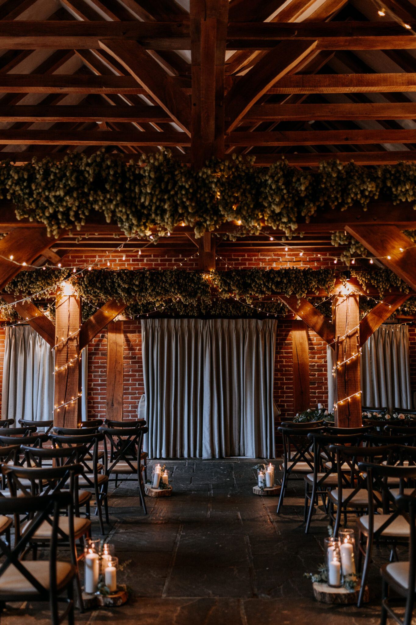 Fairy lit wedding barn decorated for a winter ceremony with hops and aisle candles