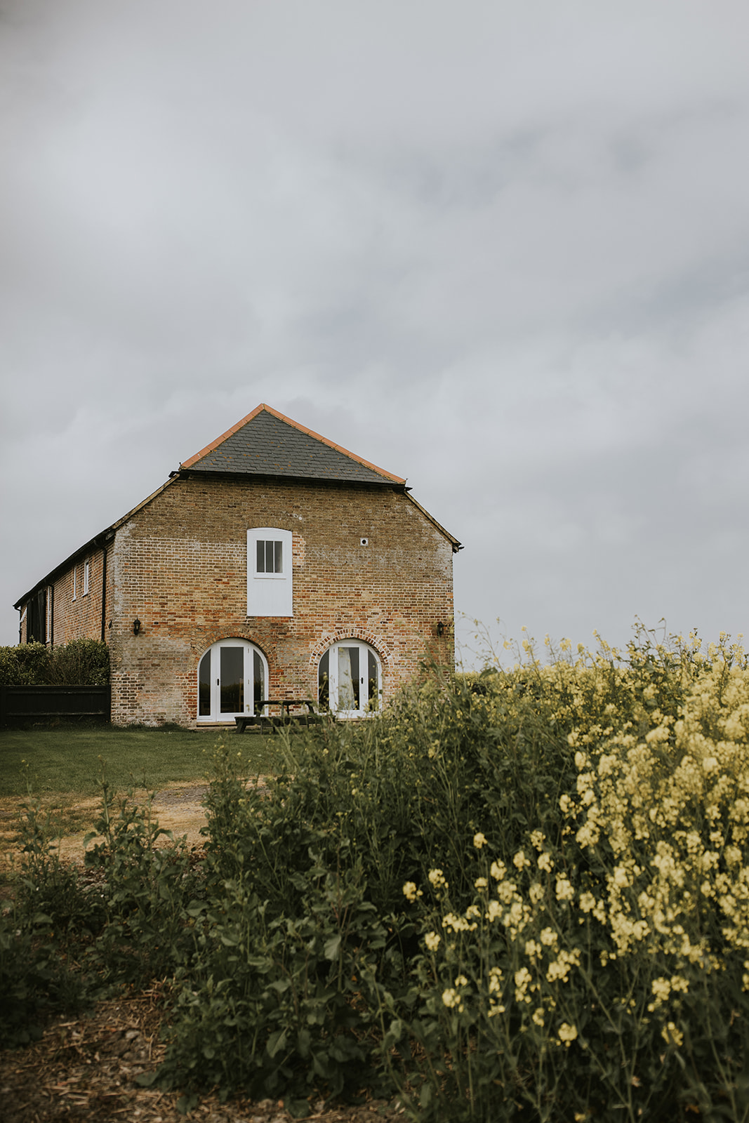 Country cottage exterior with rapeseed flowers at a barn wedding venue with accommodation