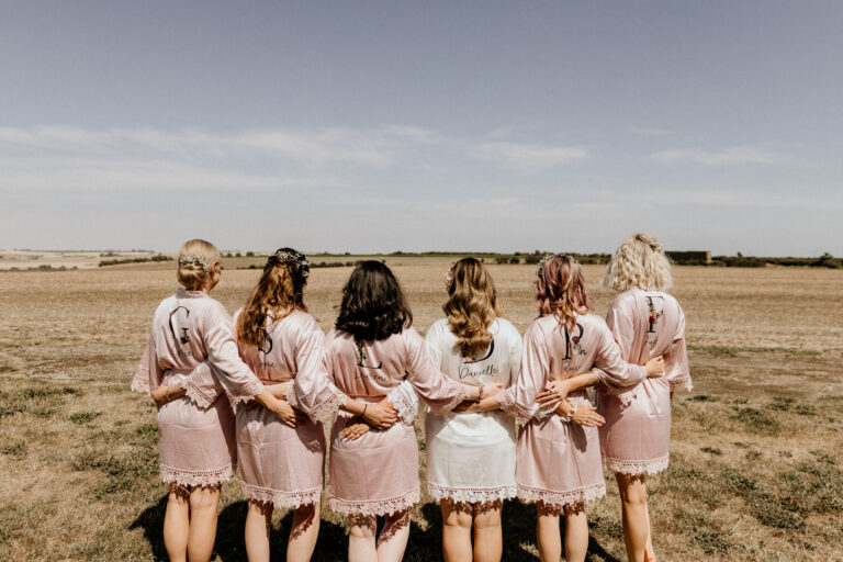 Bridal party in matching pink dressing gown stand arm in arm as they look over the Kent countryside