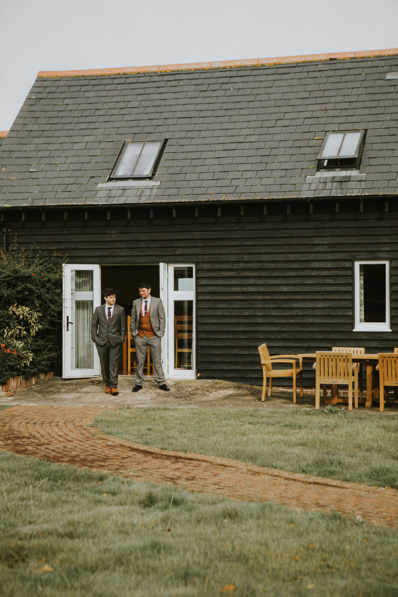 Two wedding groomsman stand outside their Kent country cottage accommodation