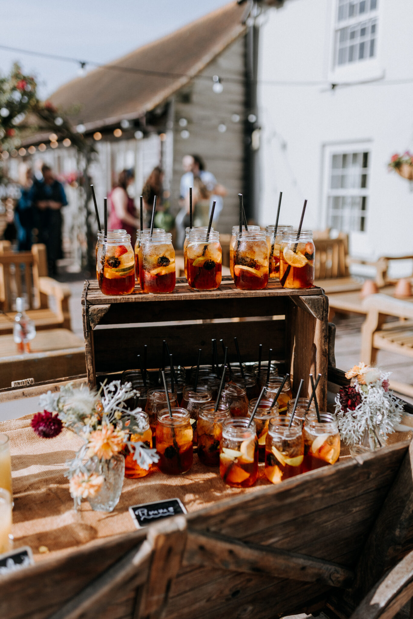 Pimms in rustic jars on a vintage cart during a sunny barn wedding drinks reception