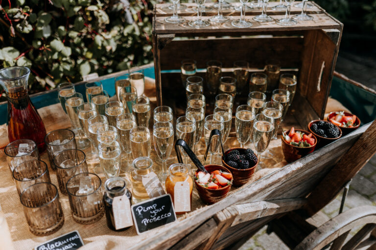Prosecco and garnishes served outdoors on a vintage cart at a barn wedding in Kent