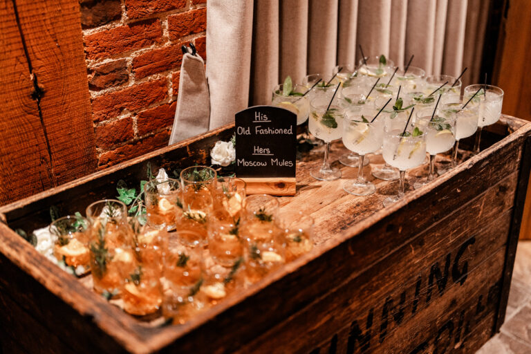 Elegant cocktails served on a antique wooden cart in a rustic Kent wedding barn