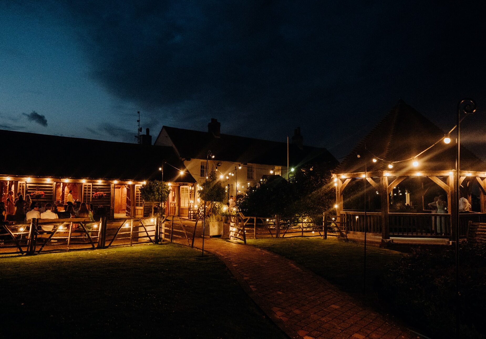 Night view of The Harty Estate's Ferry House and wedding barn lit by festoon lights