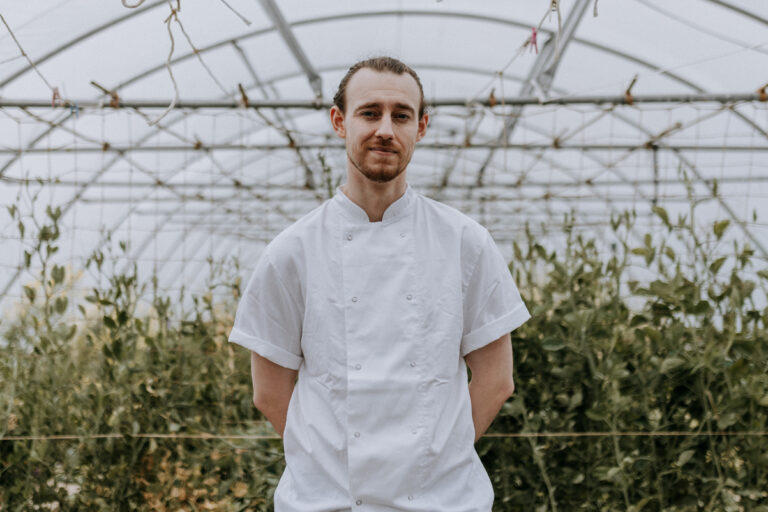 Chef standing in a polytunnel giving a Kitchen Garden tour during a corporate event