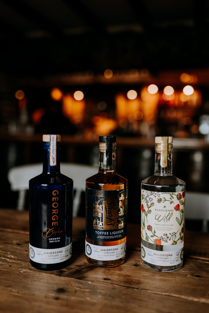 Three bottles of gin in a rustic bar ready for a corporate tasting event