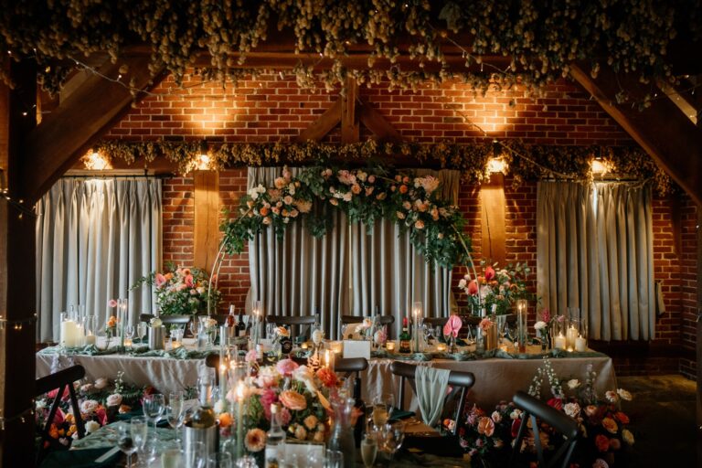 Rustic barn wedding venue in Kent dressed with hops and a pink floral arch for a wedding breakfast