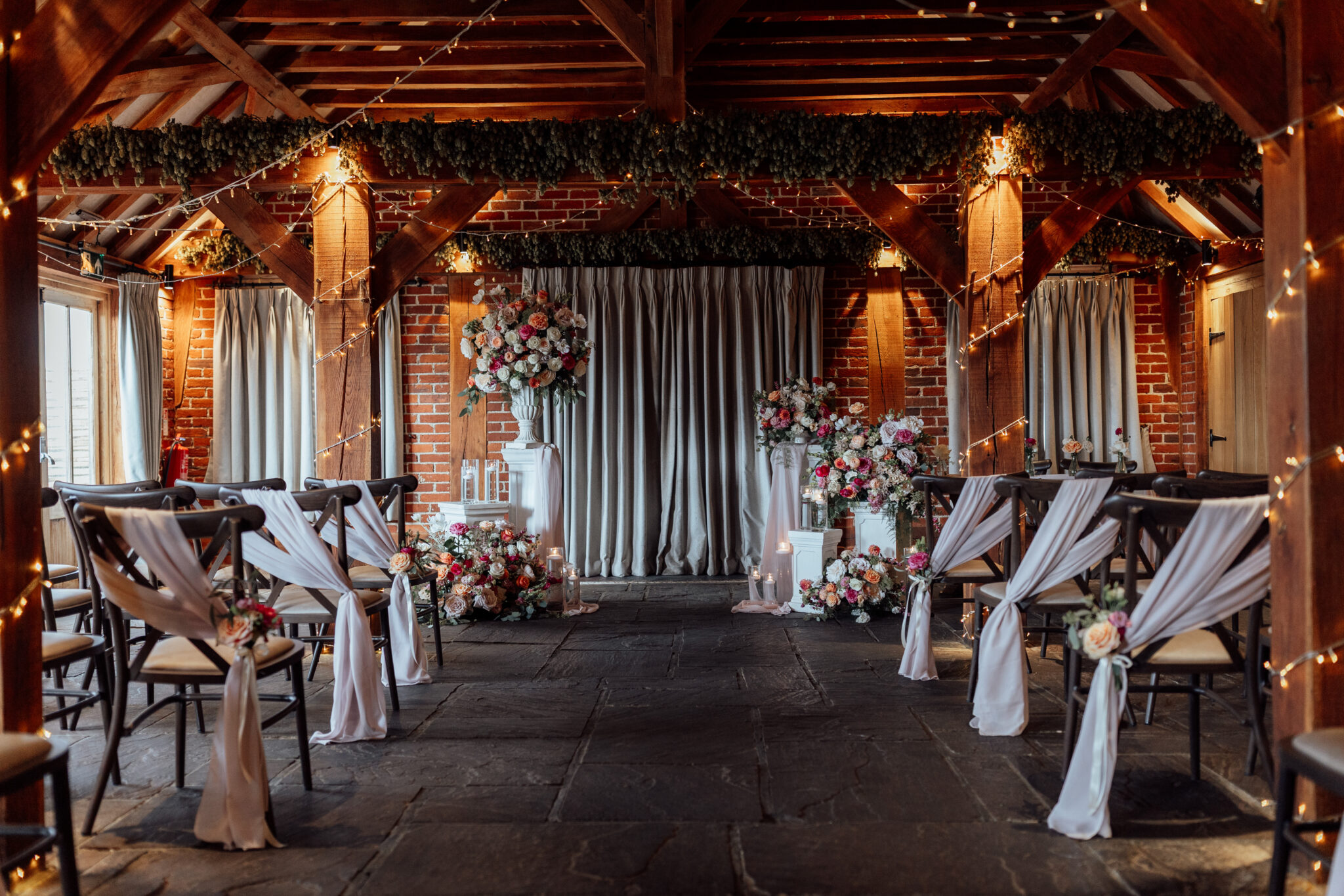 Rustic wedding barn styled for a ceremony with white floral pillars