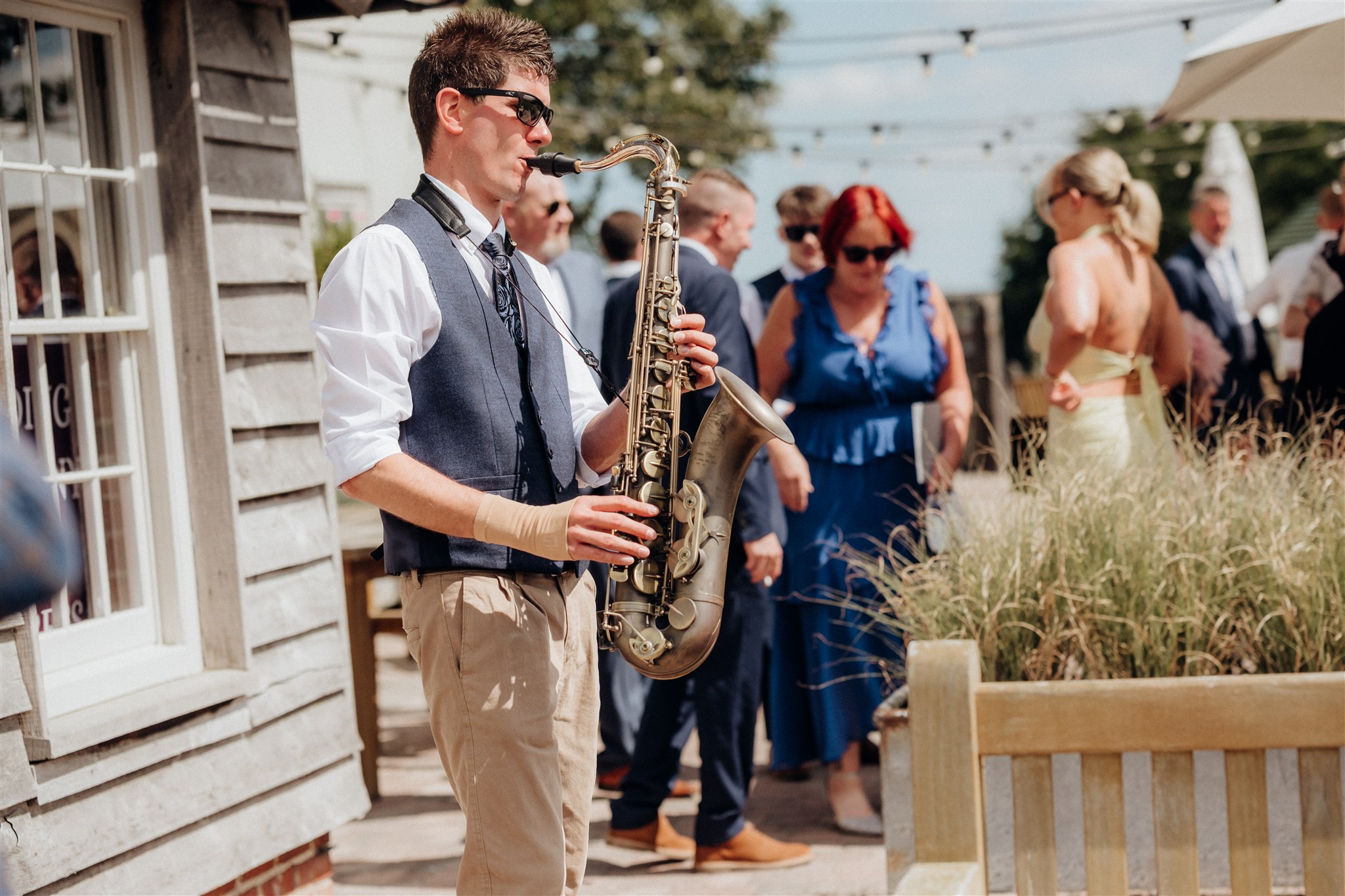 Kent wedding saxophonist entertains guests outdoors during a sunny barn wedding
