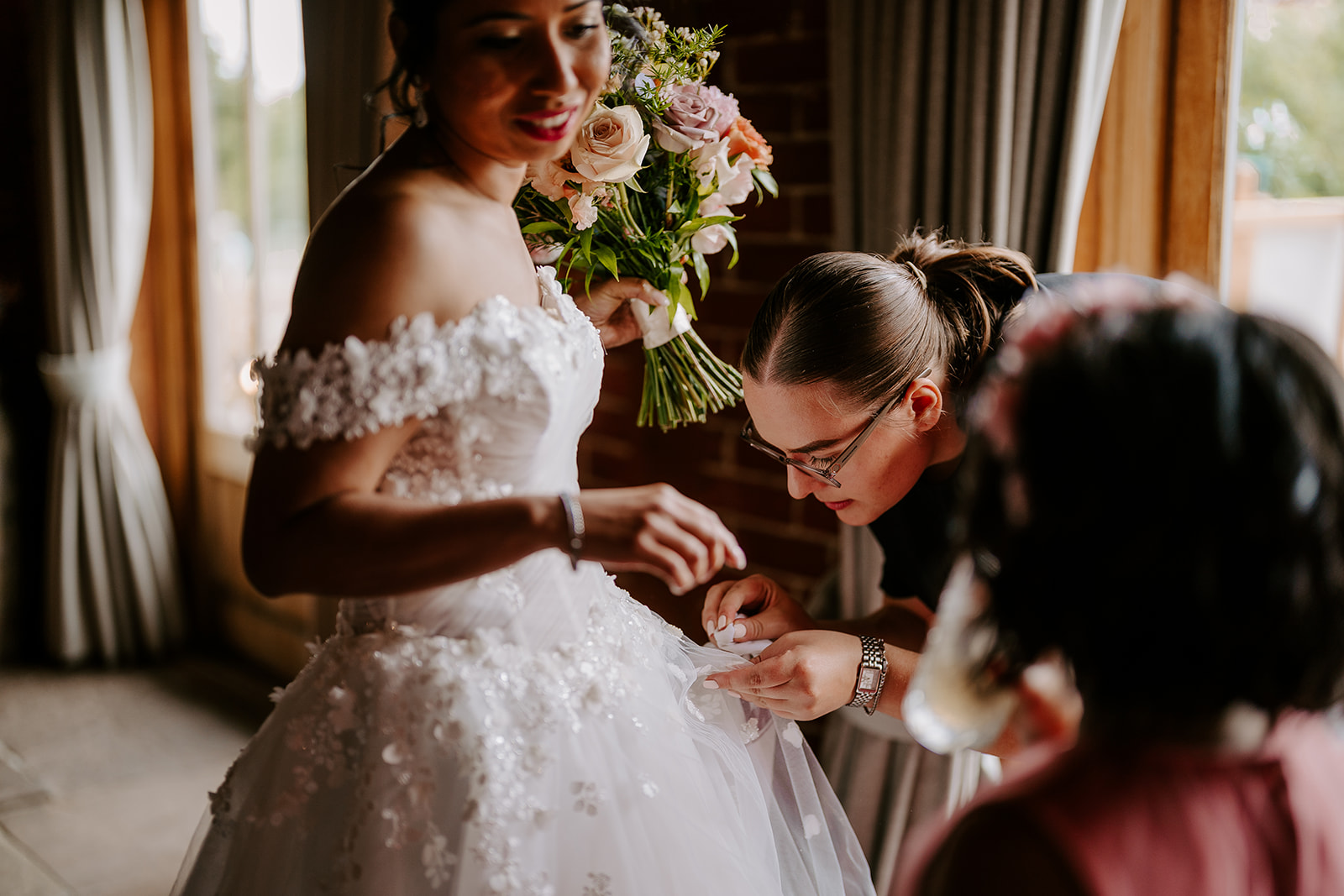 Wedding coordinator helps a happy bride with her wedding dress