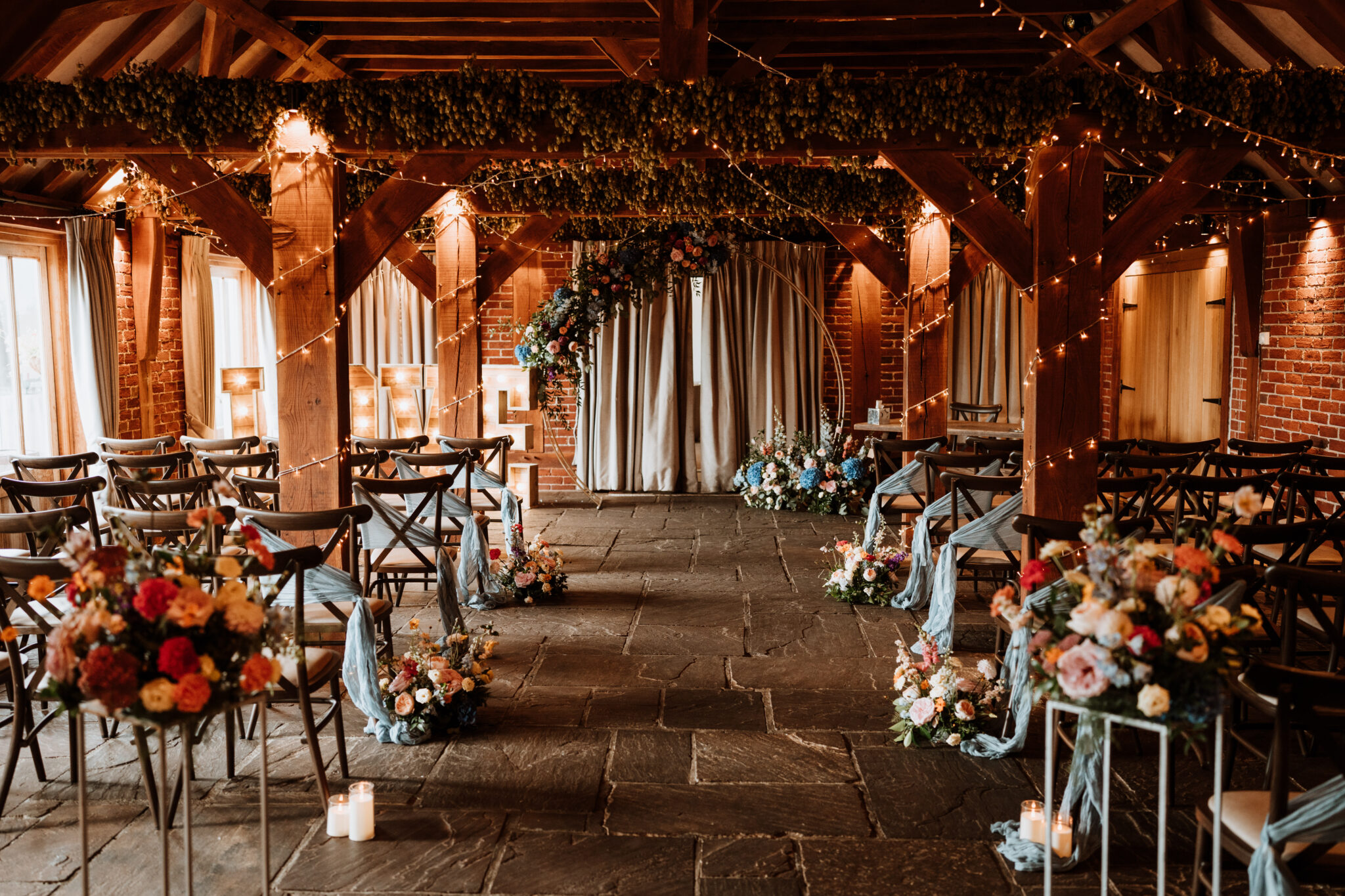 Barn wedding ceremony with flower-lined aisle and moongate