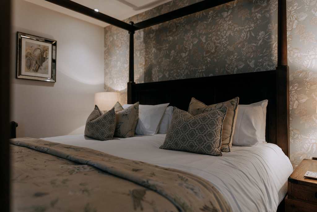 Four poster bed and lit lamp at The Harty Estate room 6