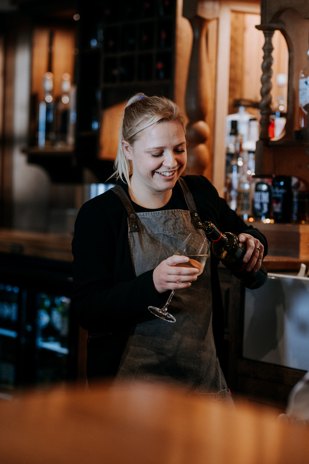 Smiling hospitality staff member pouring a drink