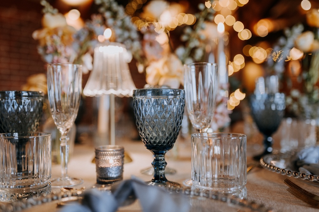 A wedding breakfast table with spring seasonal blooms, lamps and cut glasswear
