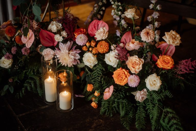 Vibrant, colourful wedding flower display with candles
