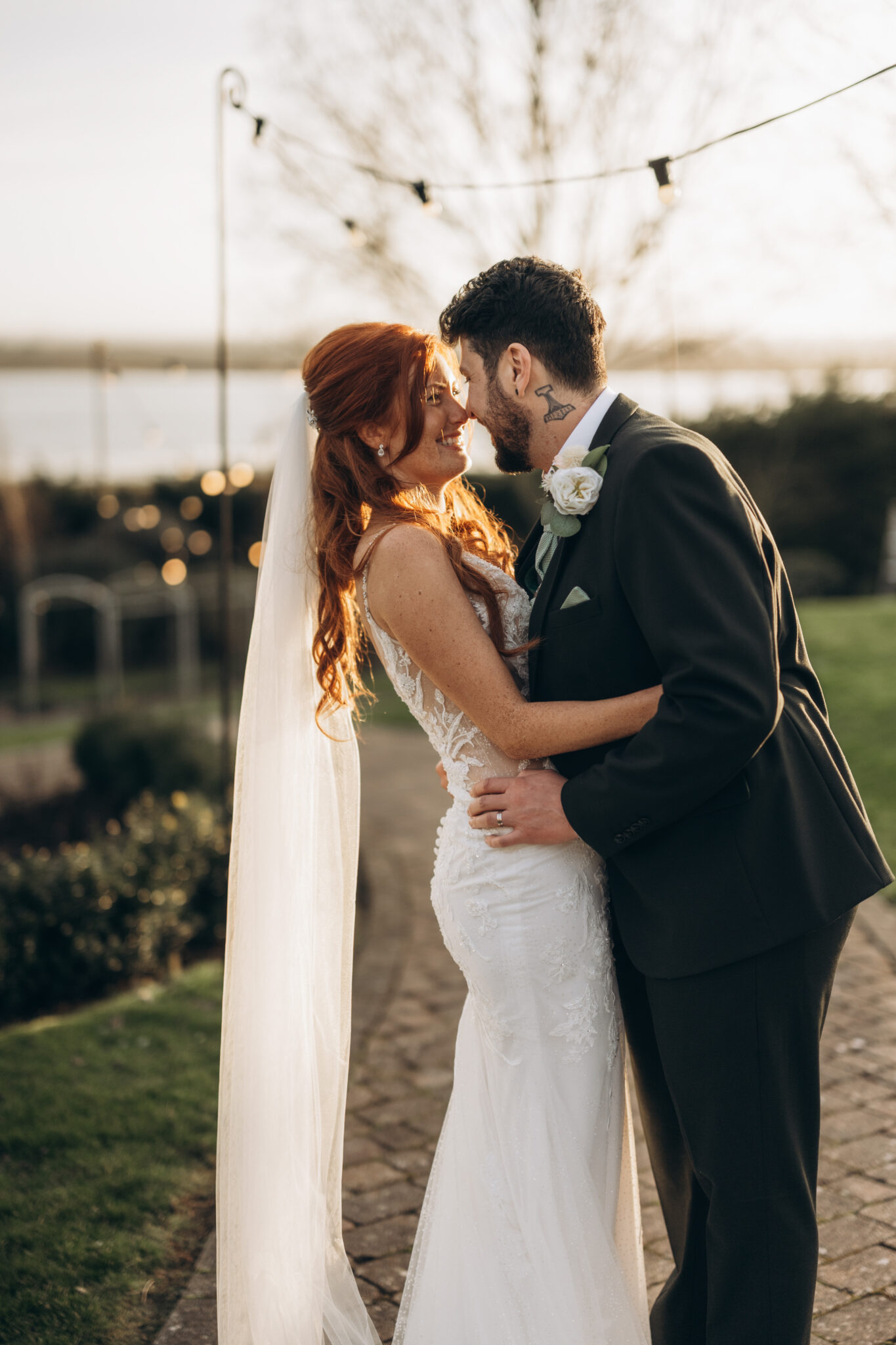 Newlyweds laugh and embrace in a festoon lit winter wedding garden