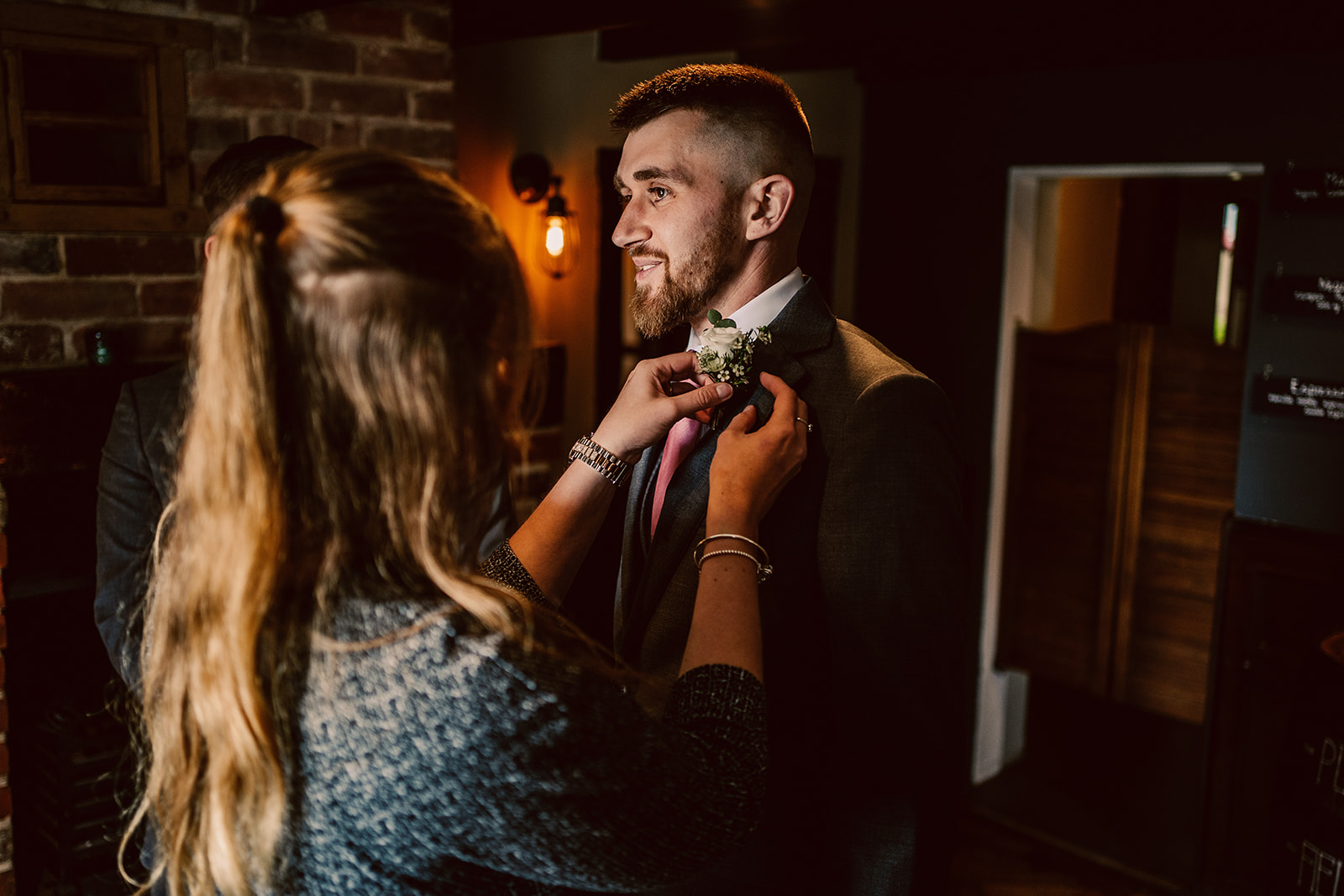 Wedding coordinator helping a groom with his button hole