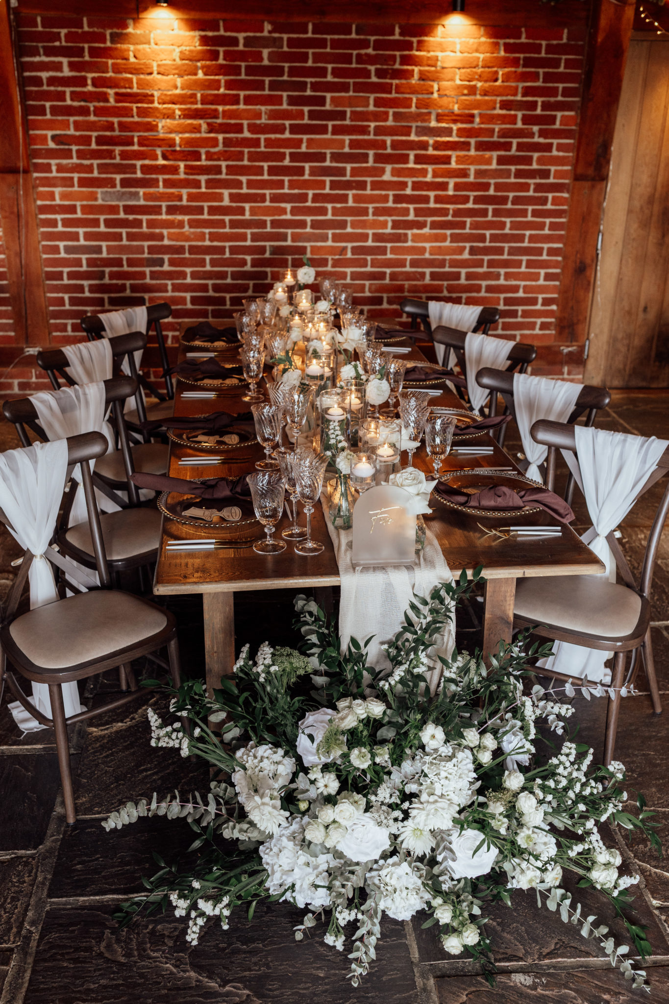 Intimate wedding breakfast table styled with white and green florals, table runner and chair sashes