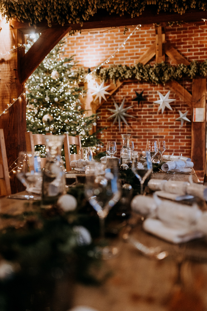 Table laid for a Christmas party, in a rustic event barn with Christmas tree and hops